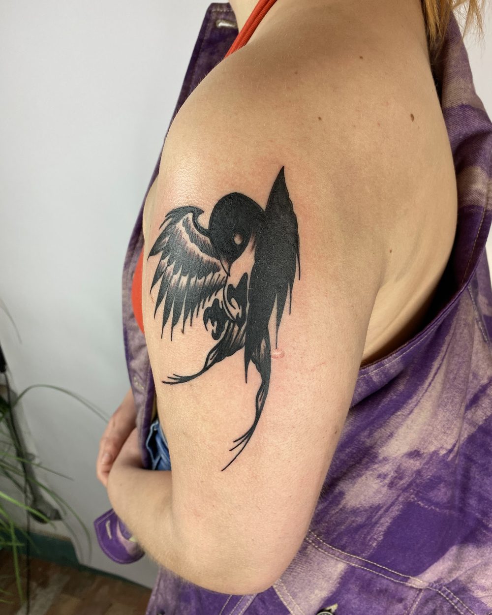 Winged demon figure in illustrative blackwork on an upper arm