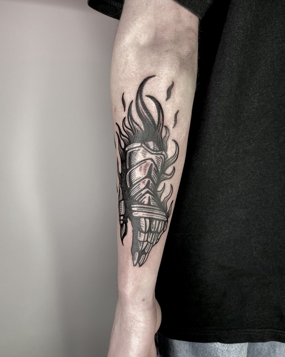 Bird lifting out of brush-drawn ink strokes on a forearm